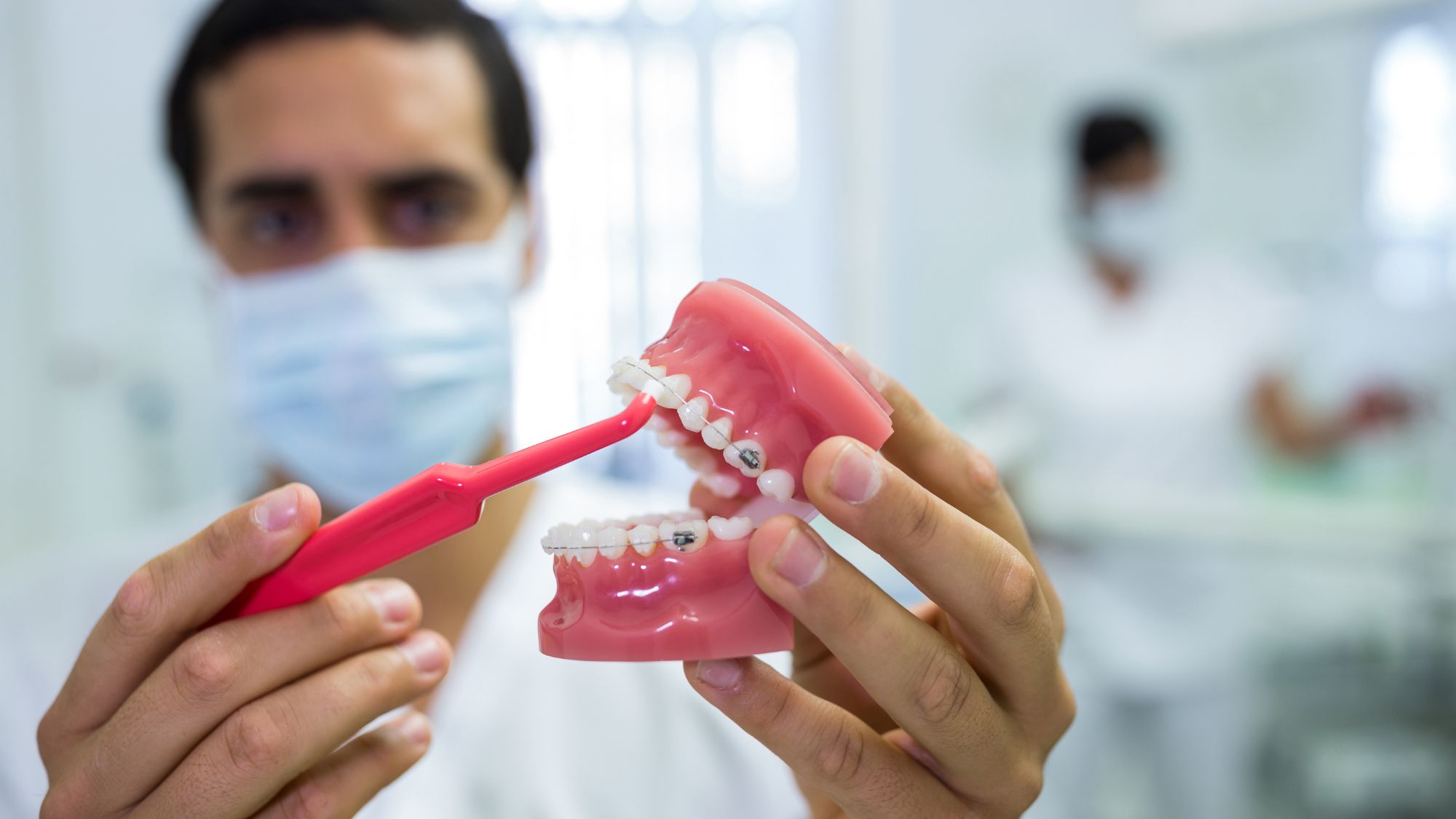 A dentist is holding a denture set, comparing full dentures and partial dentures