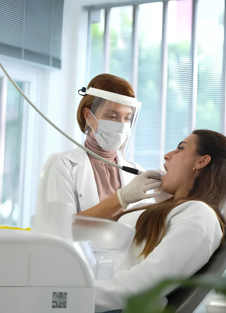 Dentist providing gentle dental treatment to a patient at a Tucson dental office using protective face shield and modern equipment